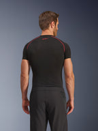 Achteraanzicht van een model in Alpinestars Aeroshell Airflow broek, zwart, lichtgewicht softshell constructie met geïntegreerde mesh zijpanelen, gecombineerd met een zwarte basislaag met rood contraststiksel, sportieve motorkleding