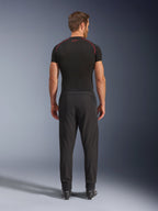 Alpinestars Aeroshell Airflow broek, zwarte motorbroek, achteraanzicht getoond op een model met een zwarte basislaag en laarzen, voorzien van een lichtgewicht softshell-chassis met geïntegreerde mesh-panelen voor ventilatie
