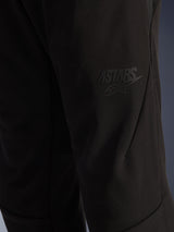 Alpinestars Aeroshell Airflow broek, zwarte motorbroek, close-up van het dijgedeelte met een verhoogd zwart ASTARS-logo, lichtgewicht stretch softshell materiaal met ergonomisch naadontwerp