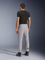 Achteraanzicht van een model dat de Alpinestars Aeroshell Airflow broek in Mid Gray draagt, gecombineerd met een zwart basislaag shirt en zwarte schoenen, waarbij de laser-geperforeerde zones op de kuiten en de sportieve pasvorm worden benadrukt.