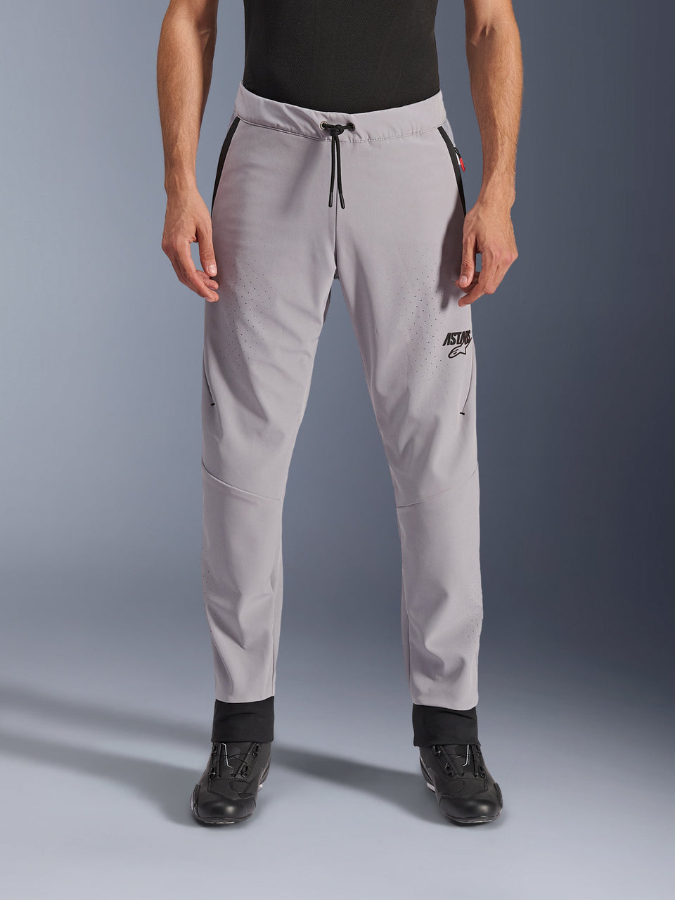 Alpinestars Aeroshell Airflow broek, Mid Gray, vooraanzicht met laser-geperforeerde zones op de dijen en schenen, zwarte tailleband met trekkoord en zwart ASTARS-logo, lichtgewicht softshell-chassis voor rijden in warm weer