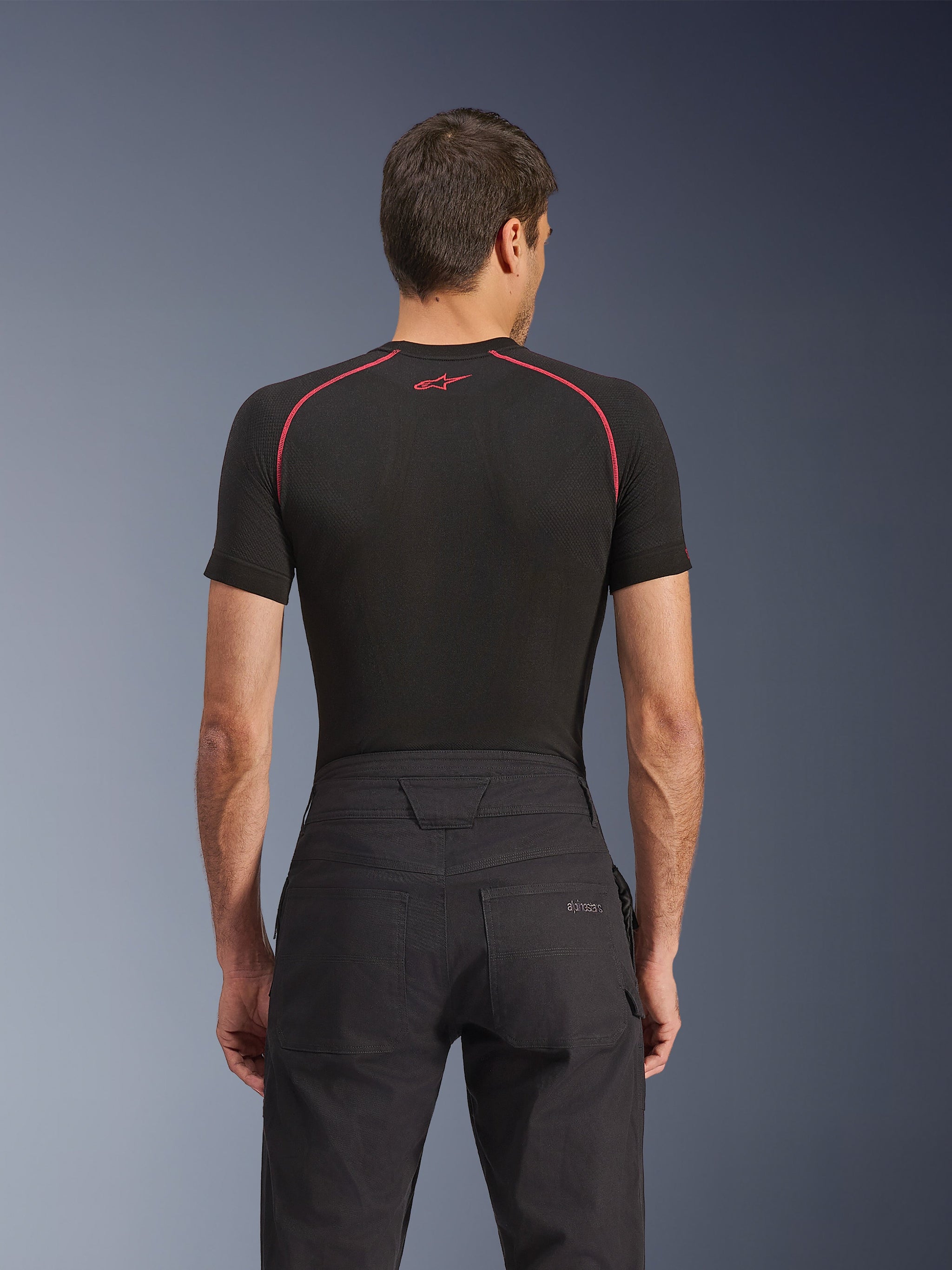 Alpinestars Flex-AST Canvas Pants, urban motorbroek, zwart, achteraanzicht met de achterzak voorzien van een geborduurd Alpinestars-logo, verstevigde tailleband en contrasterende stiksels, gestyled met een zwarte performance basislaag.