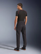 Alpinestars Flex-AST Canvas broek, zwarte urban motorbroek, achteraanzicht op model, gecombineerd met een zwarte basislaag met korte mouwen en zwarte sneakers, voorzien van een op werkkleding geïnspireerd ontwerp met grote achterzakken en een moderne rechte pasvorm.