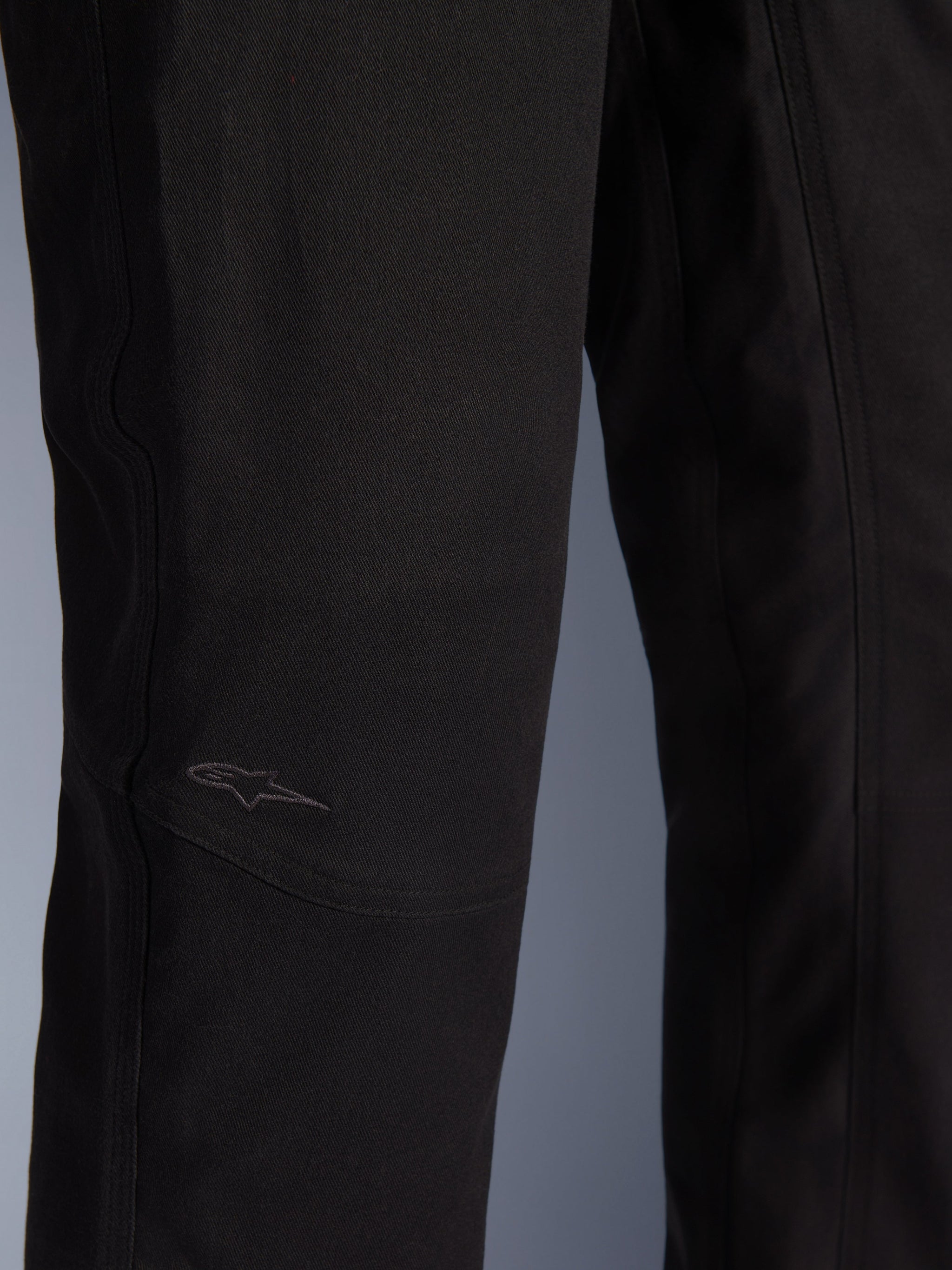 Alpinestars Flex-AST Canvas broek, urban motorbroek, zwart, close-up van het kniegedeelte met voorgevormde panelen en een subtiel geborduurd logo op duurzame canvasstof.