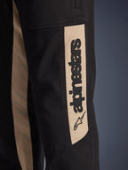 Alpinestars Flex-AST Canvas broek, close-up detail van de zijkant van de broekspijp, zwart met Aluminum beige accentpaneel, voorzien van een verticaal zwart Alpinestars-logo en ster-icoon, duurzame polykatoen twill voor stedelijk motorrijden