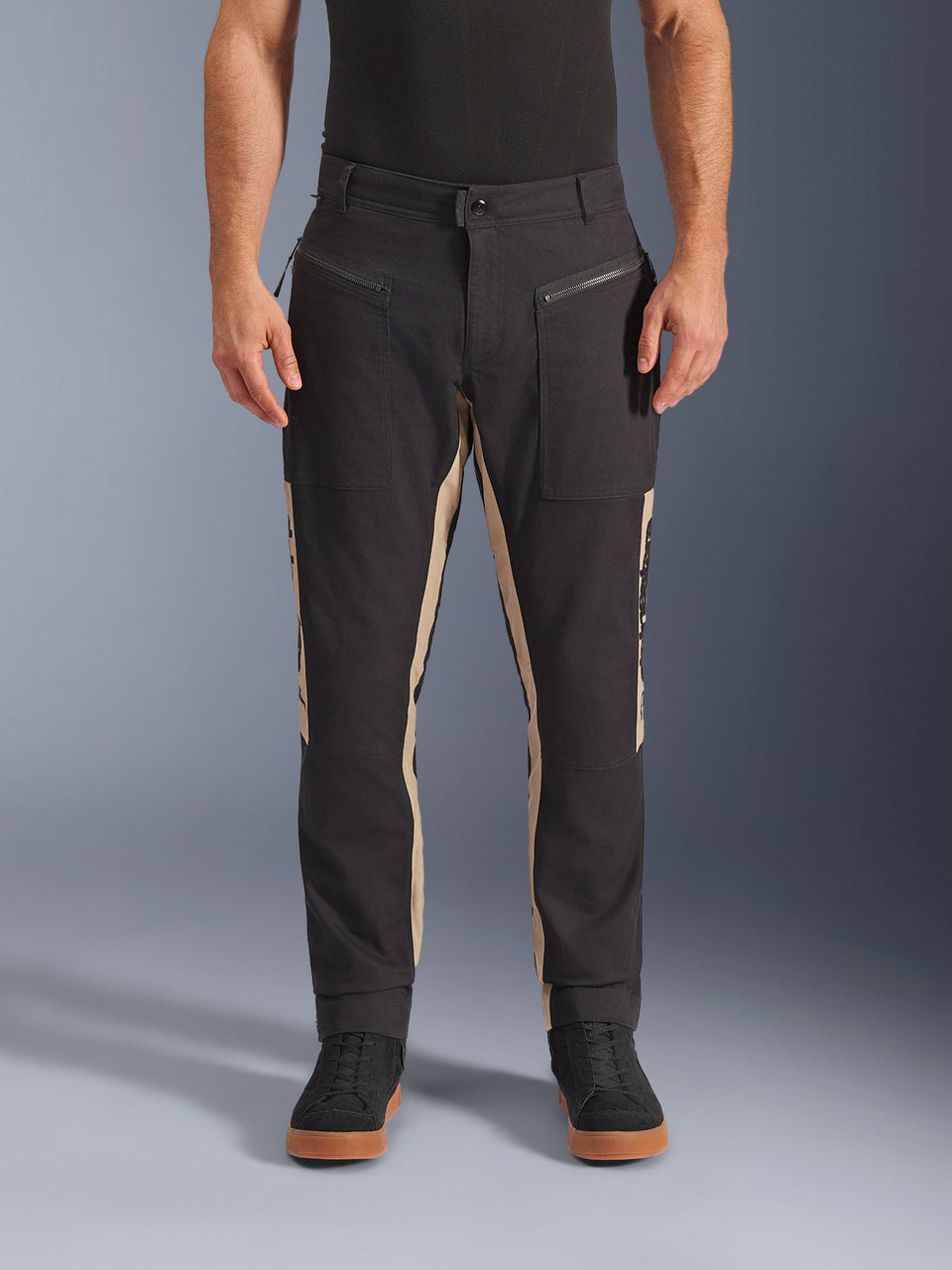 Alpinestars Flex-AST Canvas broek, urban motorbroek, zwart en aluminium, op werkkleding geïnspireerd ontwerp, voorzakken met rits, ergonomische motorpasvorm, gedragen met casual zwarte sneakers en zwart t-shirt, utilitaire street style