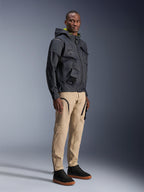 Alpinestars Acteon broek, urban motorbroek, zandkleur, gedragen door een model met een donker technisch jack en zwarte sneakers, voorzien van een taps toelopende pasvorm met zwarte ritsaccenten en cargozakken, eigentijds op de motorsport geïnspireerd ontwerp