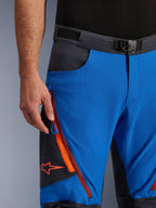 Alpinestars Maxdura Dual broek in Royal Blue en Deep Gray, close-up van de tailleband met magnetische gesp, cargozak met ritssluiting met oranje details en rood Alpinestars-logo, technische adventure motorkleding