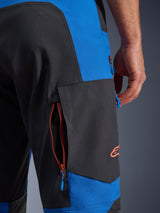 Alpinestars Maxdura Dual broek, Royal Blue en Deep Gray, close-up van de cargozak met rits aan de zijkant, blauwe ritstrekkers, oranje geborduurd logo, adventure motorrijuitrusting