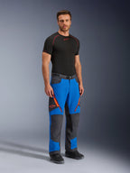Alpinestars Maxdura Dual Pants, adventure motorbroek, Royal Blue en donkergrijs, voorzien van oranje ritsaccenten en logo's, gedragen door een model met een zwarte basislaag en laarzen, technisch ontwerp met versterkte panelen voor dual-sport rijden