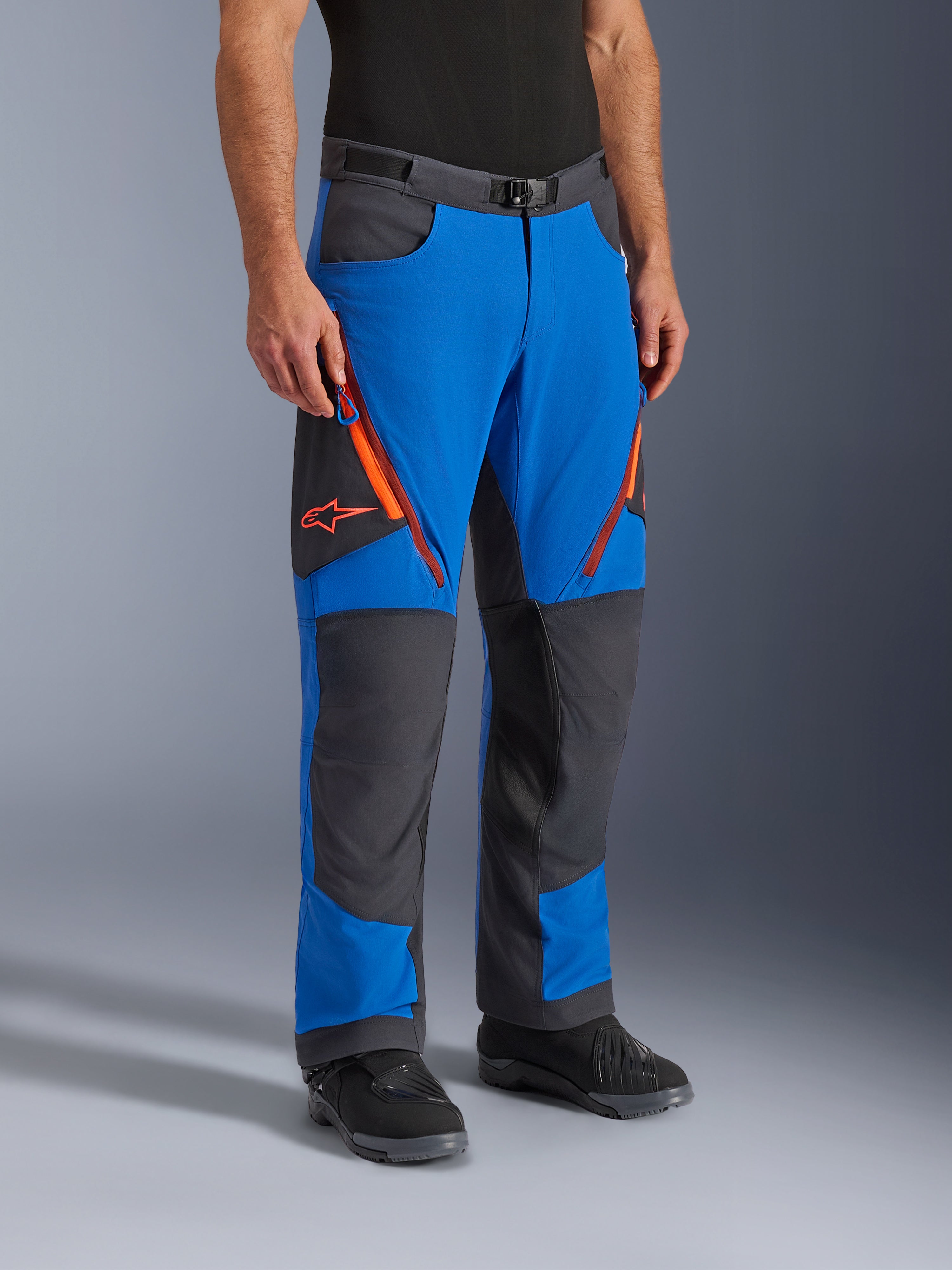 Alpinestars Maxdura Dual Pants, adventure motorbroek, koningsblauw en diepgrijs met oranje accenten, ritsventilatie op de dijen, verstevigde kniepanelen, riem met magnetische gesp, technisch over-de-laars ontwerp voor dual-sport rijden