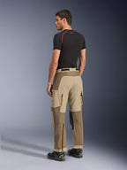 Alpinestars Maxdura Dual Pants, adventure- en dual-sport motorbroek, Walnut Aluminum, achteraanzicht gedragen door een model met een zwarte basislaag en motorlaarzen, voorzien van een multi-paneel constructie met ventilatieopeningen met rits aan de achterzijde en versterkte overlays.