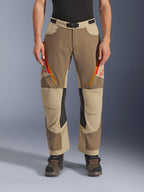 Alpinestars Maxdura Dual Pants, Walnut Aluminum, adventure motorbroek met rood en oranje ventilatieritsen op de dijen, zwarte leren binnenkniepanelen, gedragen met een zwarte basislaag en robuuste laarzen, duurzaam meerkleurig ontwerp voor dual-sport ritten