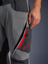 Alpinestars Maxdura Dual Pants, donkergrijze en diepgrijze adventure motorbroek, close-up van open ventilatieopening met rits op het bovenbeen met rode accenten en geborduurd rood sterlogo, technisch ontwerp van stretchstof