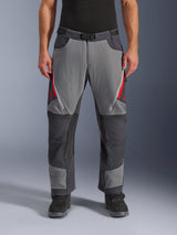 Alpinestars Maxdura Dual Pants, adventure motorbroek, donkergrijs en diepgrijs met rode accenten, vooraanzicht met dijventilatie met rits, magnetische gespsluiting en verstevigde kniepanelen, over-de-laars ontwerp voor dual-sport rijden.