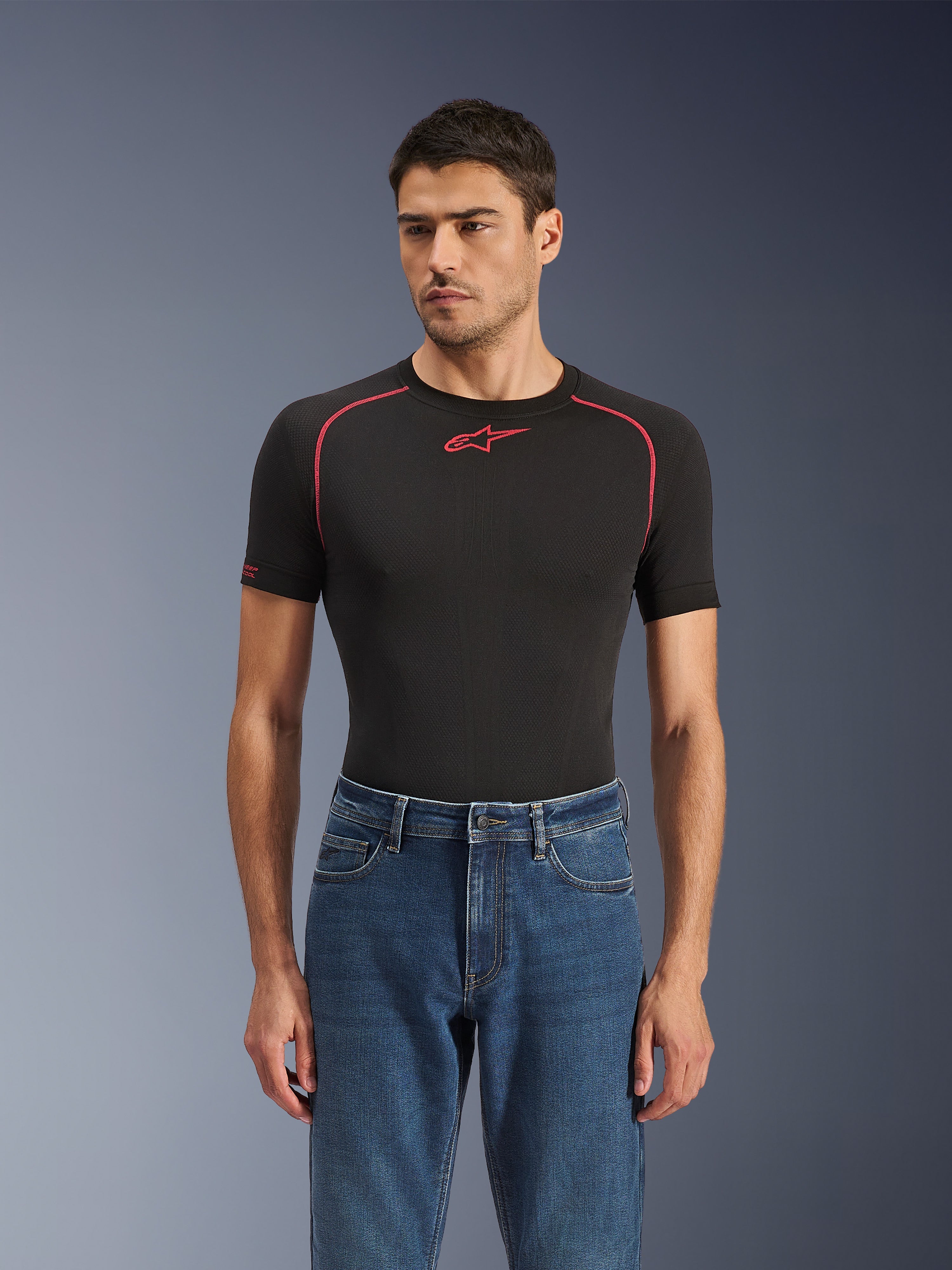 Alpinestars Flex-AST 5 Denim broek in Indigo Washed, stedelijke motorjeans met een toelopende pasvorm, gedragen door een mannelijk model met een zwarte basislaag met korte mouwen en rode accenten, casual road-to-street styling
