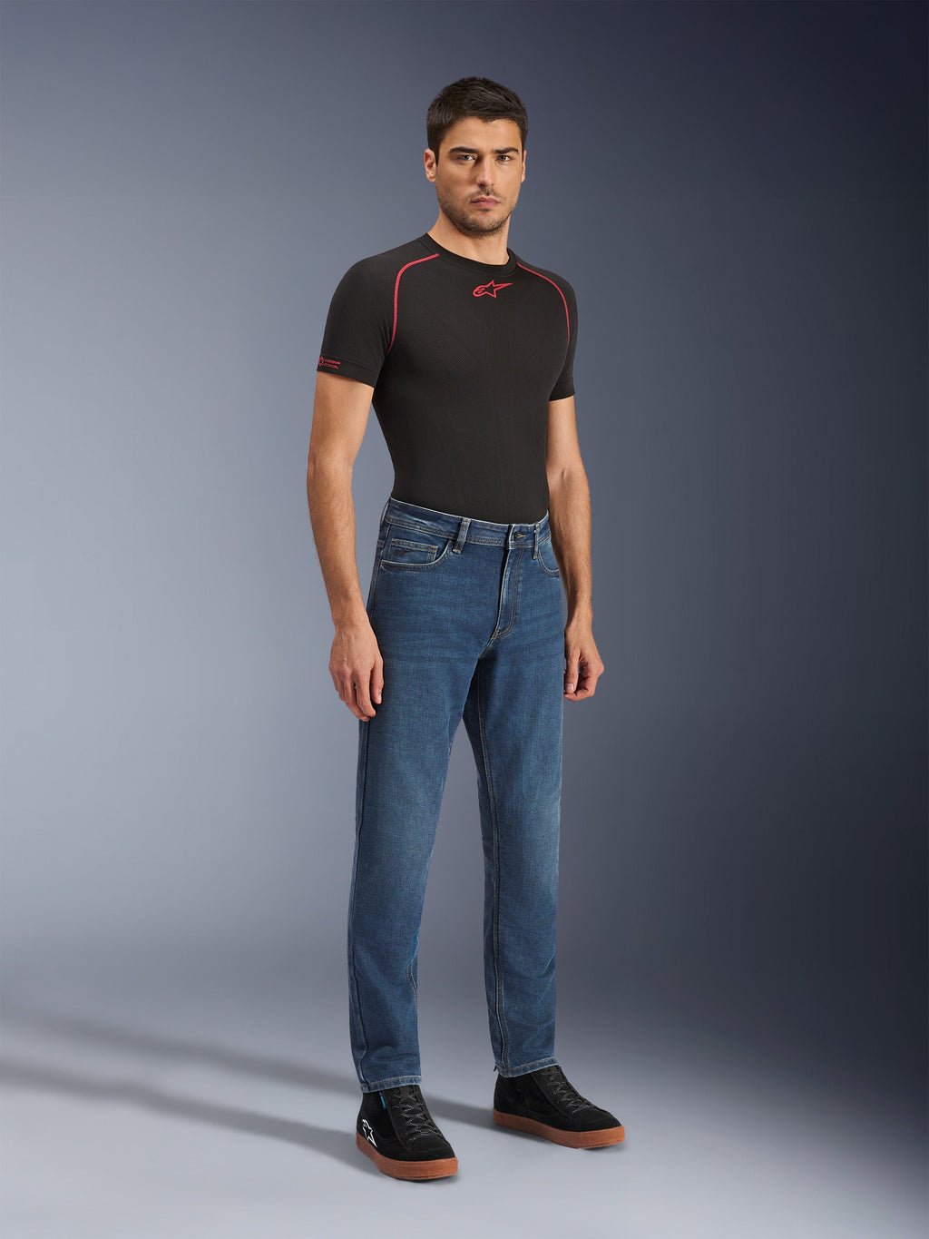 Alpinestars Flex-AST 5 Denim Pants - Short, Indigo Washed, stedelijke motorjeans met een toelopende pasvorm, gedragen door een mannelijk model met een zwart nauwsluitend shirt en zwarte sneakers, klassieke denimstijl voor overgangen van weg naar straat