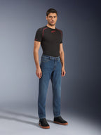 Alpinestars Flex-AST 5 Denim Pants - Short, Indigo Washed, stedelijke motorjeans met een toelopende pasvorm, gedragen door een mannelijk model met een zwart nauwsluitend shirt en zwarte sneakers, klassieke denimstijl voor overgangen van weg naar straat