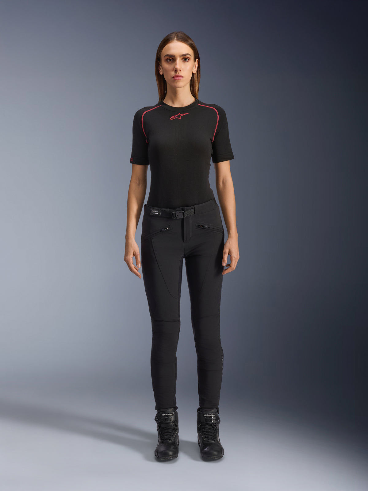 Alpinestars Alamosa damesbroek, slim-fit zwarte motorbroek, getoond op een model van voren, met ritszakken aan de voorkant en een geïntegreerde tailleriem, minimalistische op streetwear geïnspireerde stijl voor stedelijk rijden