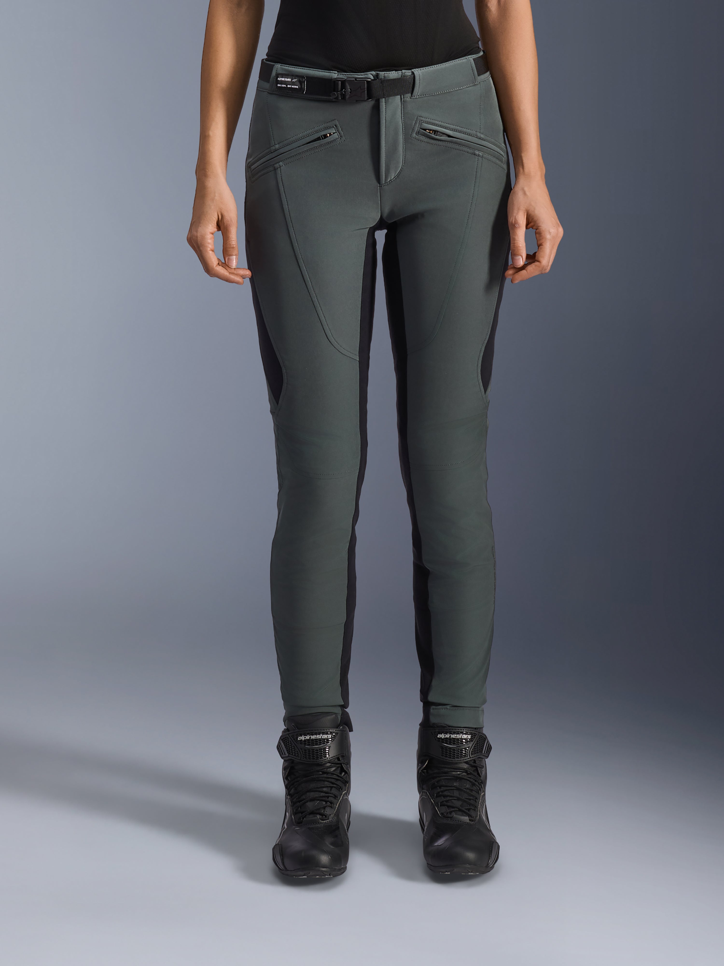 Alpinestars Alamosa dames-motorrijbroek, grijs en zwart met zijpanelen, slim fit, gedragen met zwarte motorlaarzen.