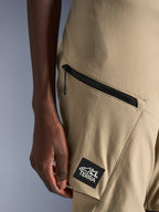 Alpinestars Stella Flex-AST Explorer broek, motorbroek voor dames, zandkleur, close-up van een cargozak met ritssluiting en zwarte ALL TERRA-logopatch, duurzame ripstop-textielconstructie voor adventure touring