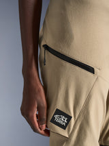 Alpinestars Stella Flex-AST Explorer broek, motorbroek voor dames, zandkleur, close-up van een cargozak met ritssluiting en zwarte ALL TERRA-logopatch, duurzame ripstop-textielconstructie voor adventure touring