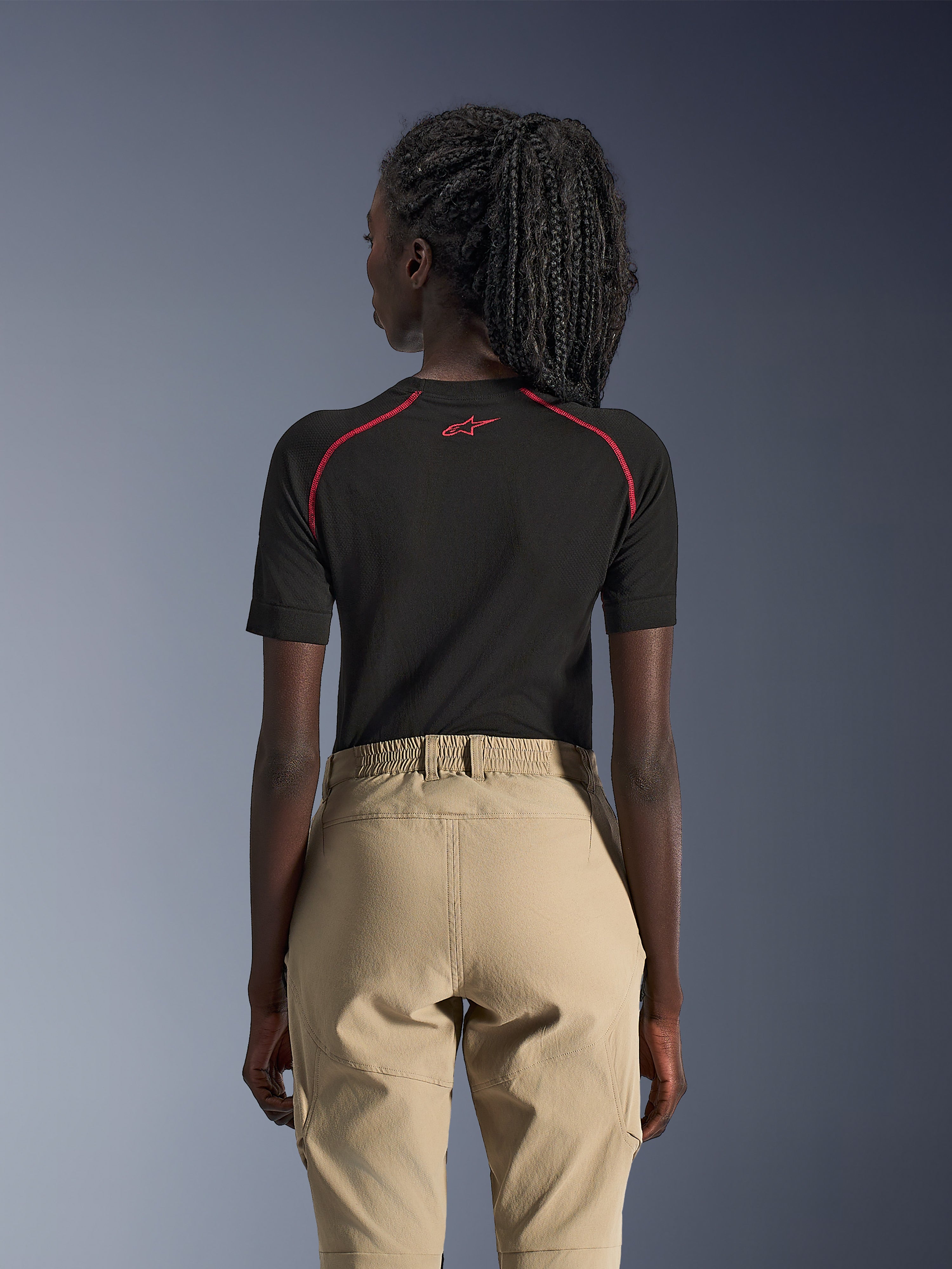 Alpinestars Stella Flex-AST Explorer damesmotorbroek, zand, adventure motorbroek, achteraanzicht gedragen met een zwarte basislaag met korte mouwen en rode accenten, voorzien van een elastische tailleband en duurzame textielconstructie