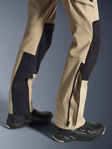 Alpinestars Stella Flex-AST Explorer broek, dames motorbroek, zandkleur en zwart, close-up van de onderbenen met een ritssluiting bij de zoom voor pasvorm over laarzen, gedragen met zwarte Alpinestars motorschoenen, voorzien van duurzame ripstop en ademende stretchstof panelen.