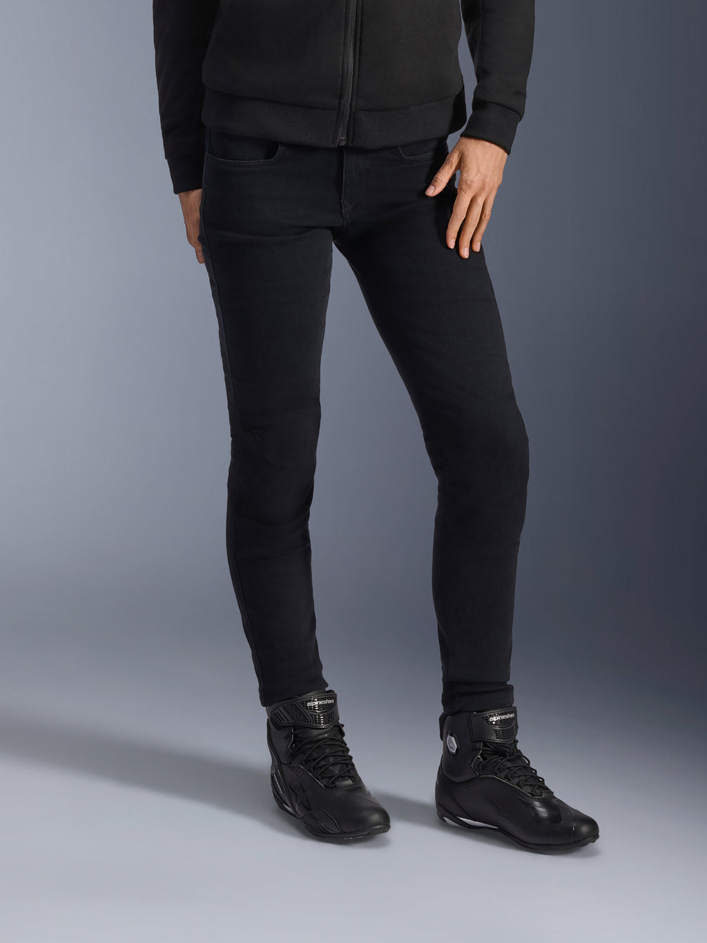 Alpinestars Daisy V3 dames motorjeans, Rinse Black, slim-fit motorbroek, gecombineerd met zwarte hoge motorschoenen en een hoodie met ritssluiting, strakke monochrome urban styling