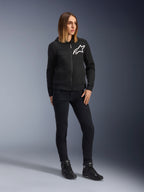 Vrouw draagt Alpinestars Daisy V3 Riding Denim voor dames, slim-fit motorbroek in Rinse Black, gecombineerd met een zwarte hoodie met ritssluiting en motorlaarzen, urban casual beschermende kleding