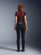 Alpinestars Daisy V3 dames motorjeans, Rinse Black, slim-fit motorbroek van achteren gefotografeerd, met een high-waist ontwerp en achterzakken, gecombineerd met een rood en zwart technisch shirt met patroon en zwarte laarzen, urban motorkleding voor dames