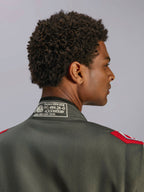Alpinestars GP Race V3 Suit FIA, Anthracite Red racing suit, close-up of back collar showing FIA 8856-2018 certification label and red shoulder epaulettes, detailed view of professional motorsport apparel.