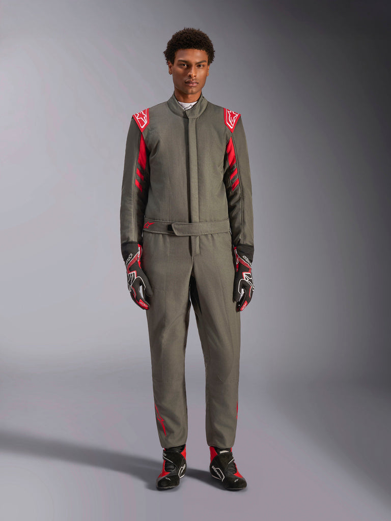 Alpinestars GP Race V3 Pak FIA, autoracepak, antraciet rood, gedragen door een mannelijk model met bijpassende handschoenen en laarzen, voorzien van rode schouderepauletten en logo's, professionele motorsportuitrusting voor prestatiegericht rijden.