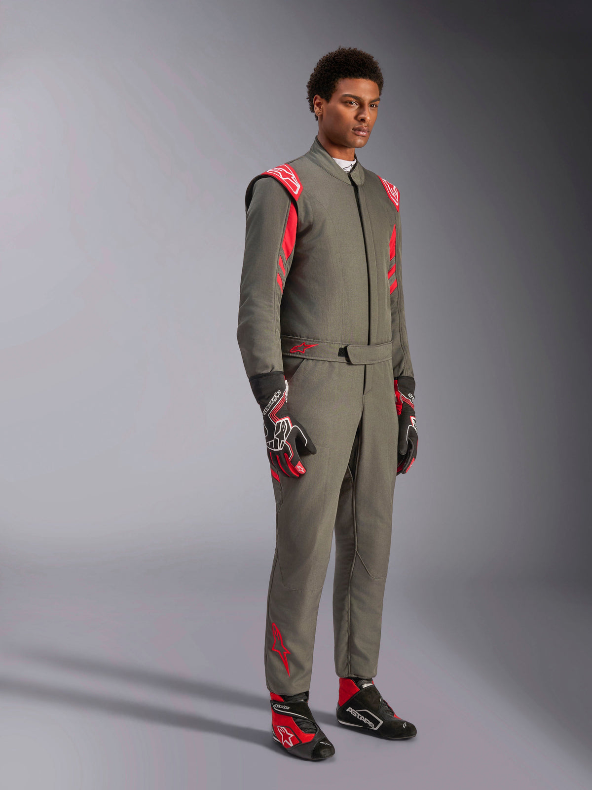 Alpinestars GP Race V3 Suit FIA, Antraciet Rood autoracepak, gedragen met bijpassende racehandschoenen en -schoenen, voorzien van rode schouderepauletten en branding, strak tweelaags technisch ontwerp voor de autosport
