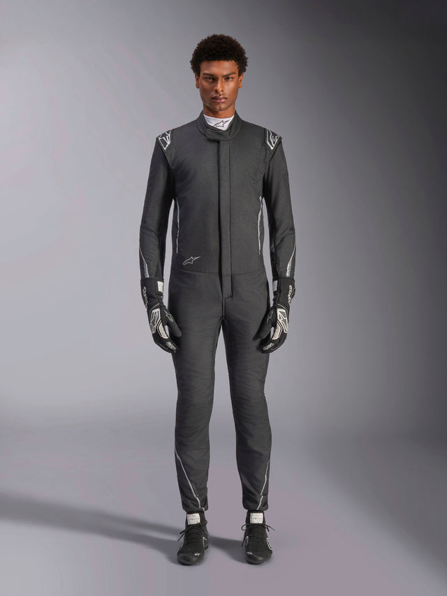 Alpinestars Hypertech V3 Suit, professional auto racing suit, Black and Dark Shadow, worn by a model with matching racing gloves and shoes, slim athletic fit with silver accents and branding, performance motorsport gear