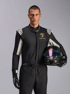 Alpinestars Limited Edition Lamborghini GP Tech V4 Suit, Auto Racing Suit, Black Silver and Gold, worn by a model holding a carbon fiber helmet with an iridescent visor, featuring Lamborghini Squadra Corse branding and white shoulder accents