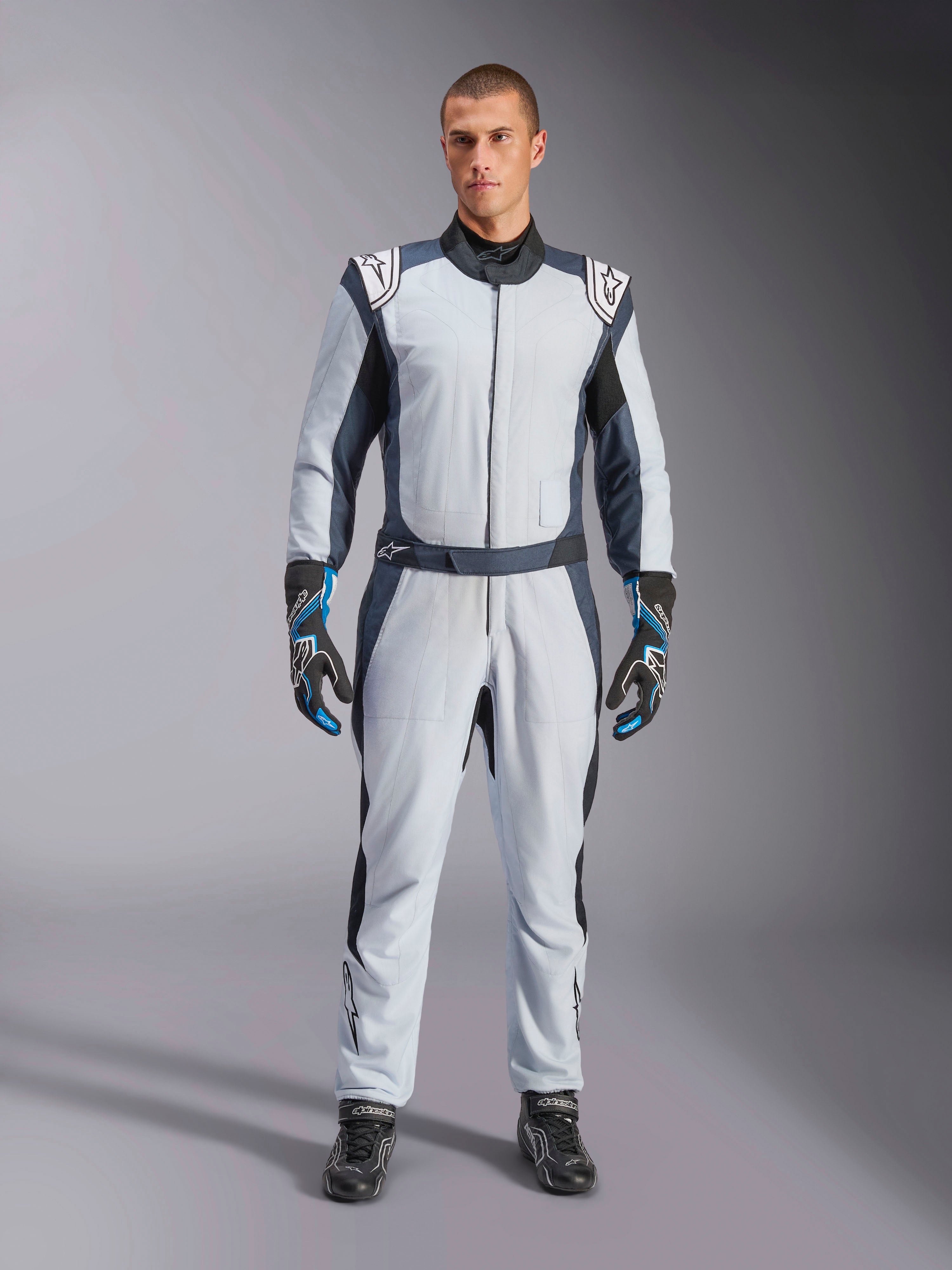 Alpinestars GP Pro Comp V2 FIA pak, zilverblauw en asfalt autoracepak, FIA-gecertificeerd aramidisch ontwerp, op model.