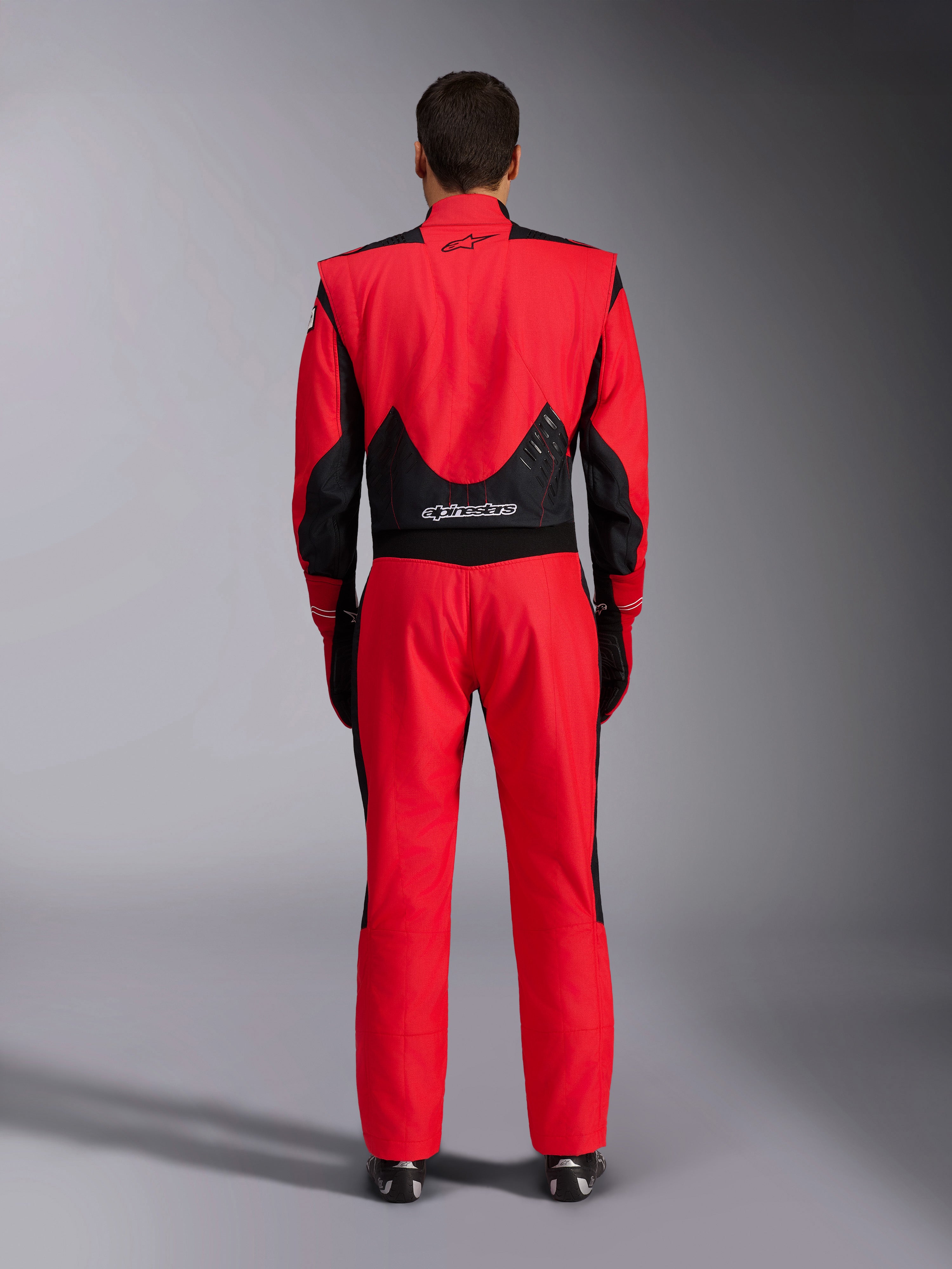 Alpinestars GP Pro Comp V2 FIA racepak, rood en zwart, achteraanzicht met zwarte mesh en stretchpanelen op de onderrug, Alpinestars-branding op de boven- en onderrug, professionele autorace-uitrusting