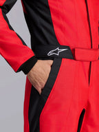 Alpinestars GP Pro Comp V2 FIA racepak, rood en zwart, close-up van de taille met een hand in de zak, zwarte riem met wit sterlogo en gestructureerde panelen voor autoracen
