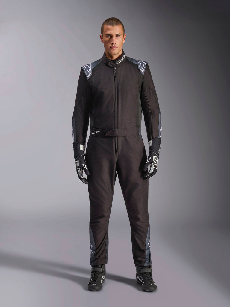 Alpinestars KMX-5 V3 pak, kartpak, Black Dark Shadow, volledig beeld van een model dat het pak draagt met bijpassende handschoenen en laarzen, voorzien van donkergrijze accenten en witte Alpinestars-logo's op de schouders en riem, professionele motorsport race-uitrusting.