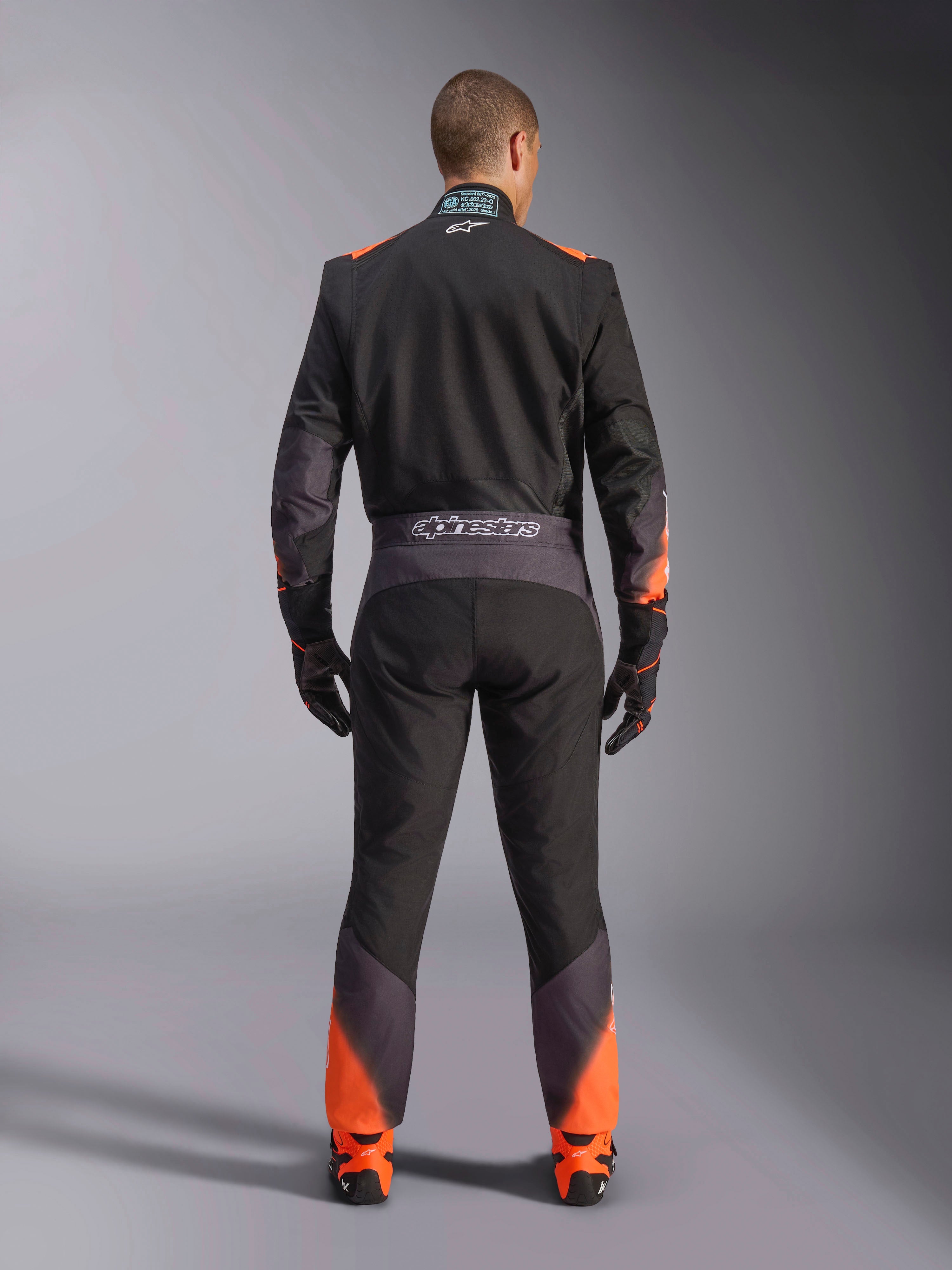 Alpinestars KMX-5 V3 pak, zwart en oranje fluo eendelig kartpak voor heren, FIA-gecertificeerd, achteraanzicht met branding.