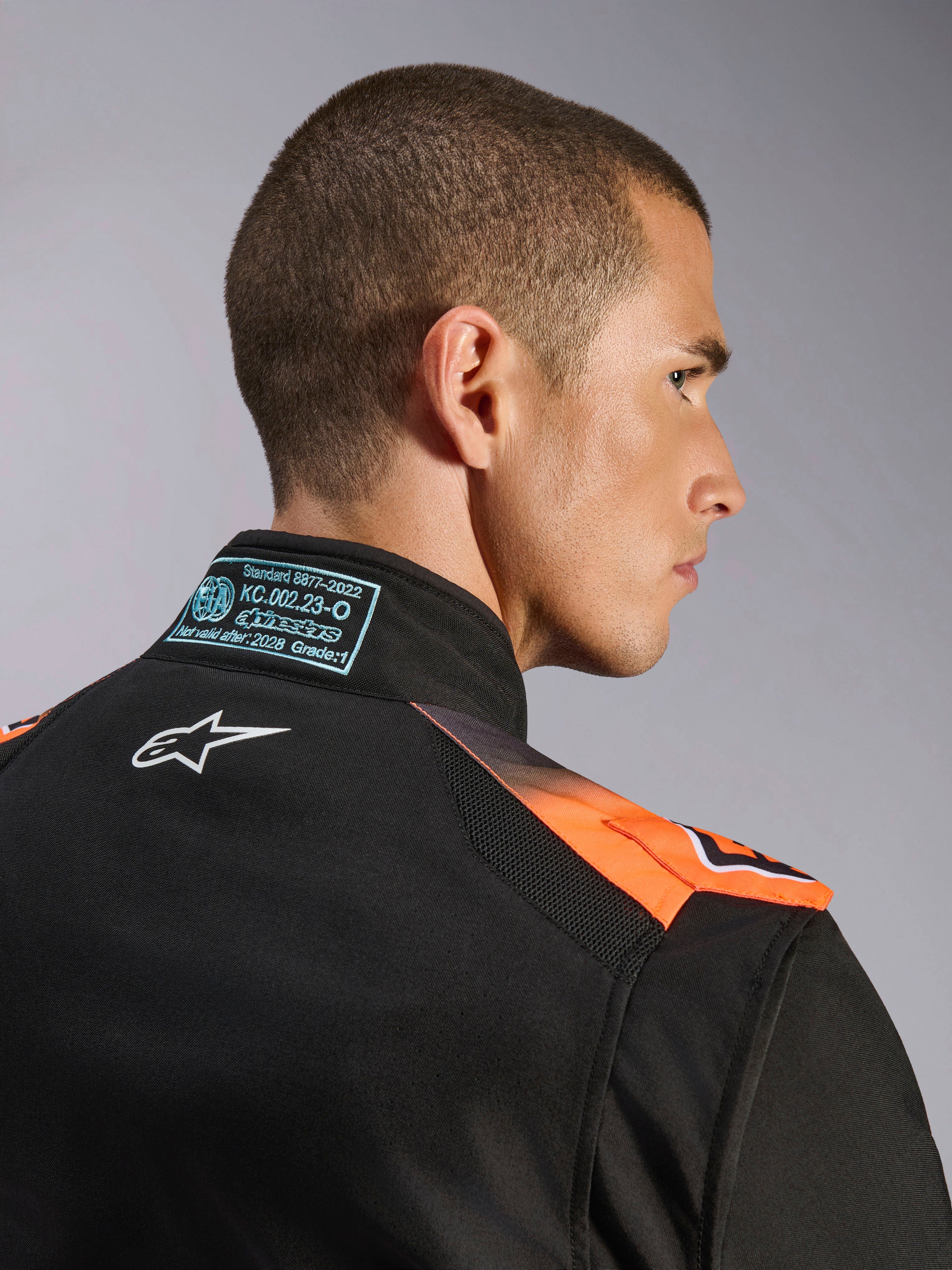 Alpinestars KMX-5 V3 pak, zwart en oranje fluo kartingpak, FIA 8877-2022 Grade 1-gecertificeerd, met technische mesh-panelen.