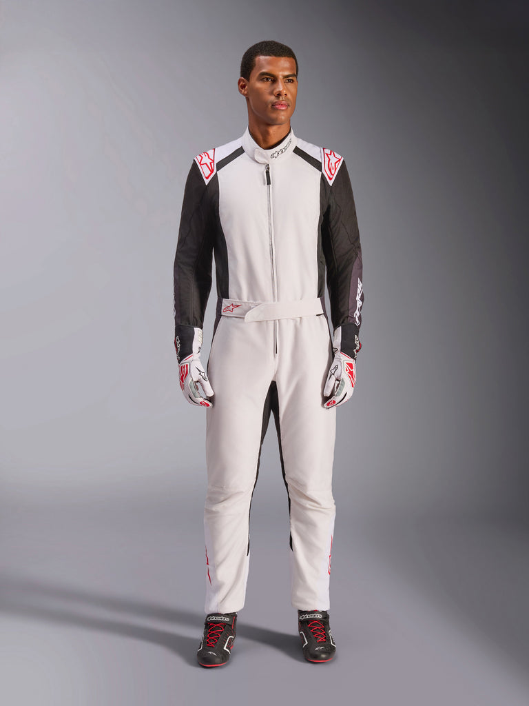 Alpinestars KMX-5 V3-pak, eendelig kartpak, wit, zwart en felrood, gedragen door een model met bijpassende racehandschoenen en raceschoenen, professionele motorsportuitrusting voor competitief karten