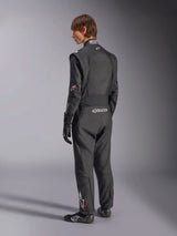 Alpinestars GP Tech V4-pak, autoracepak, zwart met witte accenten, achteraanzicht van model dat het pak draagt met racehandschoenen en -schoenen, voorzien van witte branding op de onderrug en het been, professionele autosport veiligheidsuitrusting