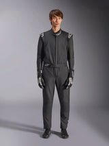 Alpinestars GP Tech V4 Suit, zwart en wit, professioneel eendelig autoracepak, gedragen met bijpassende zwart-witte handschoenen en raceschoenen, met witte Alpinestars-logo's op de schouders en kraag, strakke atletische pasvorm voor motorsportwedstrijden