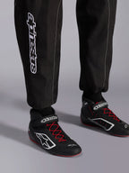 Alpinestars KMX-9 V3 Suit, Karting Suit, Black Red and White, detail view of lower legs and karting boots, white Alpinestars branding on the side, black shoes with red laces and white accents, professional motorsport racing gear.