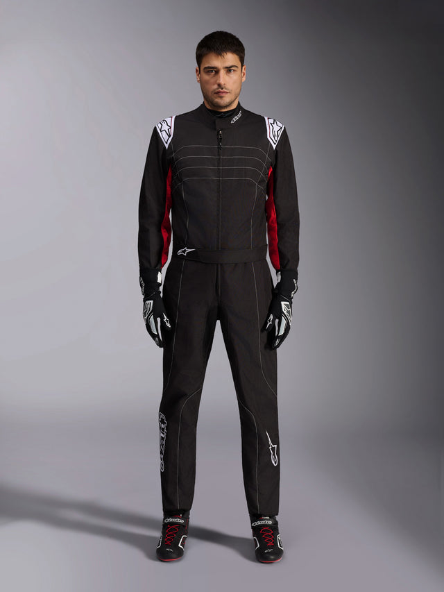 Alpinestars KMX-9 V3 Karting Suit in Black Red White, full-body front view of a model wearing the one-piece suit with coordinated racing gloves and shoes, featuring white Alpinestars logos on the shoulders and red accents.