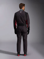 Alpinestars KMX-9 V3 Graphic 3 pak, karting pak, zwart en rood, achteraanzicht met het lumbale stretchpaneel en FIA-certificeringslabel op de kraag, gestyled met zwarte racehandschoenen en rood geaccentueerde laarzen