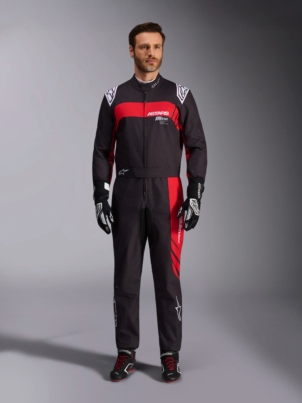 Alpinestars KMX-9 V3 Graphic 3 pak, kartingpak, zwart en rood, volledig vooraanzicht gedragen door een model, met opvallende rode grafische panelen en witte logo's, gecombineerd met zwarte racehandschoenen en schoenen, professionele motorsportkleding