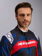 Alpinestars KMX-9 V3 Graphic 5 pak, kartpak in Navy Red, voorzien van een blauw en zwart camouflage grafisch patroon, een opvallende rode horizontale streep met witte Alpinestars tekst over de borst en witte logo's op de schouders, gedragen door een model in een studio-omgeving.